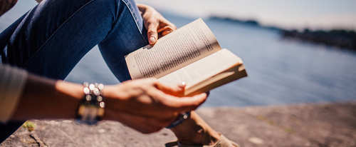 En kvinna läser en bok på en solig strand